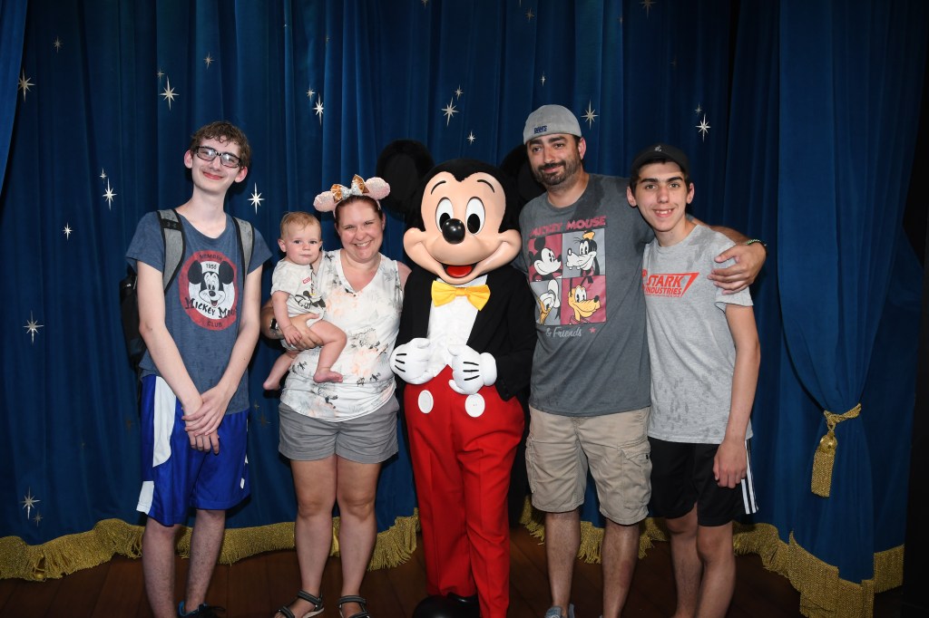 Family of 5 taking a picture with Mickey Mouse in Epcot