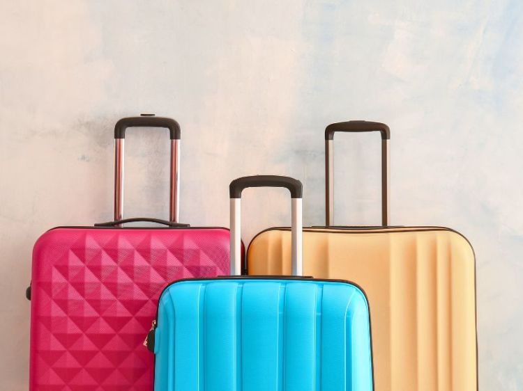 A photo of 3 suitcases, red, blue, and yellow